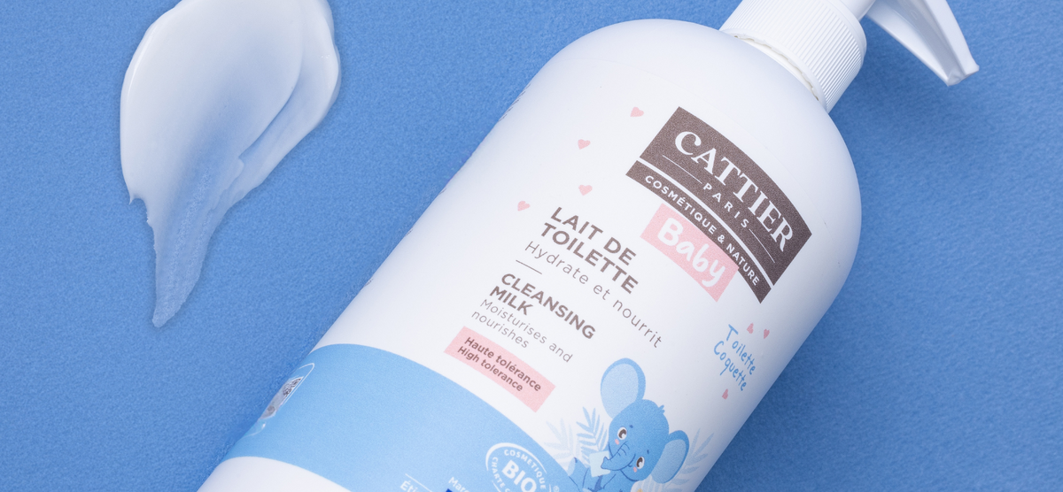 Visuel du lait de toilette bébé sur un fond bleu avec une trace de lait étalé à côté